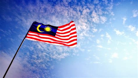 Low Angle View Of Malaysian Flag Against Blue Sky - iproperty.com.my