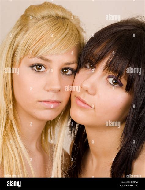 close up portrait of two beautiful girls with opposite hair color blonde and brunette stock