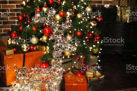 장식 된 크리스마스 트리 선물거실에서 밤에 빛나는 조명과 아름다운 크리스마스 사슴 새해 로프트 인테리어와 레드와 골드 장식 공