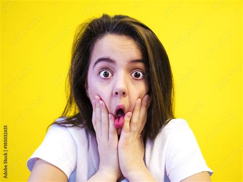 Portrait Of Surprised Girl Covering Her Mouth Looking At The Camera With Stunned And Shocked