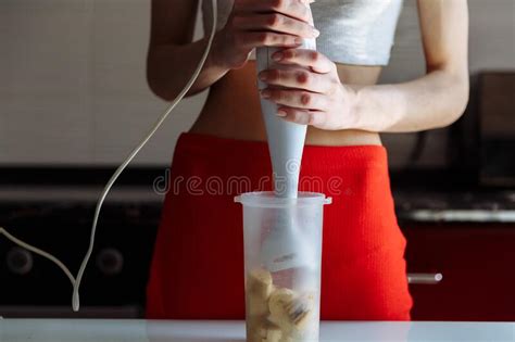 woman with hand blender making sweet banana protein milkshake sport nutrition diet after gym