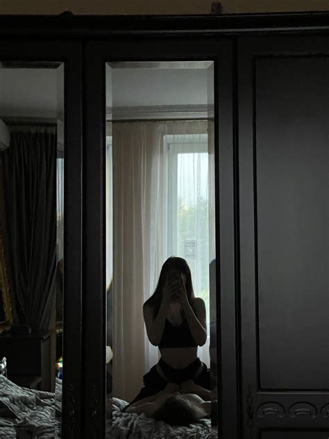 A Woman Sitting On Top Of A Bed In Front Of A Mirror