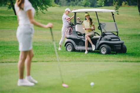 Selective Focus Of Woman With Golf Club And Friends Resting At Golf