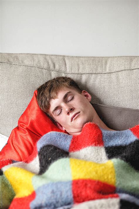 Young Man Sleeping Under A Blanket On A Couch Pormarcel