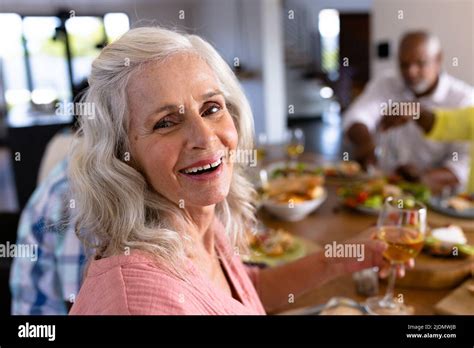 Portrait Of Senior Multiracial Woman Enjoying Wine While Having Lunch With Friends At Dining