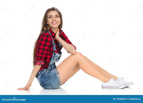 ragazza sorridente che si siede su una vista laterale del pavimento fotografia stock immagine