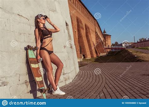 Girl In Summer In City A Longboard Skateboard Stands In Her Hand A