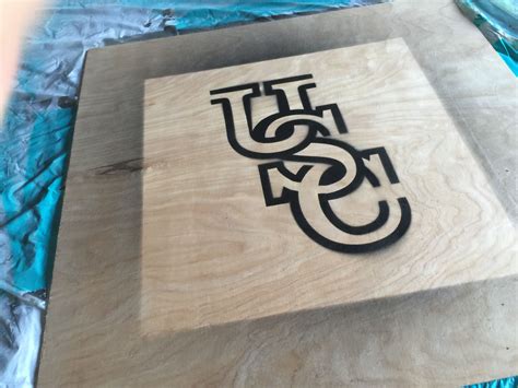 A Wooden Sign With The Word U And J On It Sitting On A Sheet Of Plastic