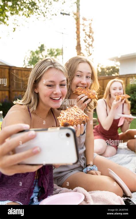 Happy Teenage Girl Friends Eating Pizza And Taking Selfie In Backyard Stock Photo Alamy