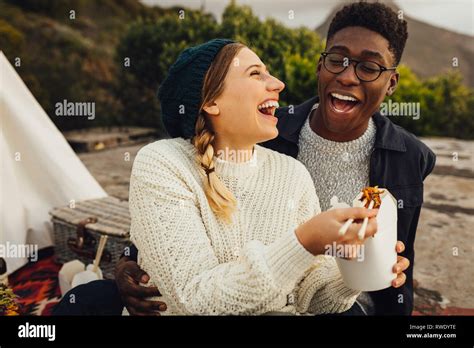 Interracial Couple Enjoying Outdoors On Picnic Woman Feeding Food To