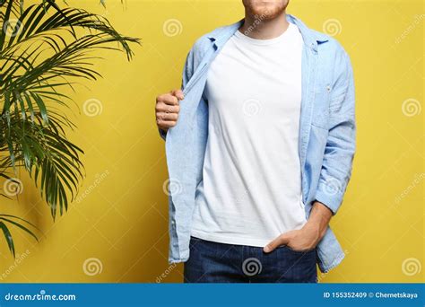 Young Man Wearing Blank T Shirt On Yellow Background Mockup For Design