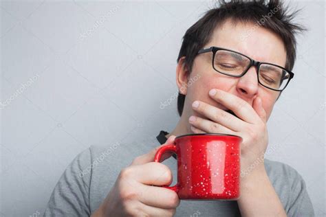 Sleepy Yawning Man In Eyeglasses With Red Cup Of Tea Or Coffee Has