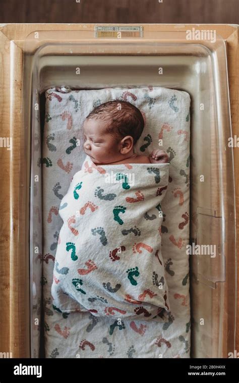 Overhead View Of Newborn Infant Boy Swaddled In Hospital Bassinet Stock