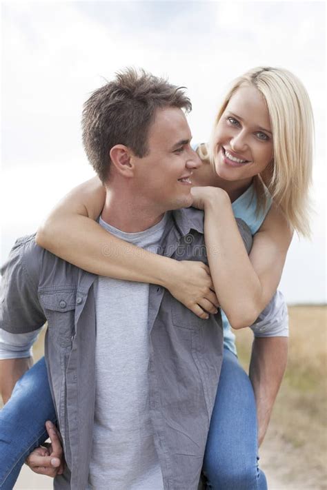 Happy Young Man Giving Piggyback Ride To Woman On Field Stock Image