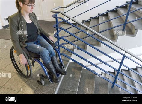 Young Handicapped Woman In A Wheelchair Stands With Her Wheelchair In A