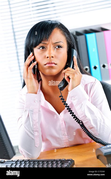 Young Black Business Woman Multitasking Using Two Phones In Office