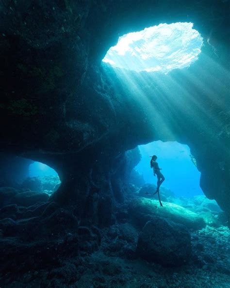 A Person Swimming In An Underwater Cave With Sunlight Streaming Through The Waters Surface
