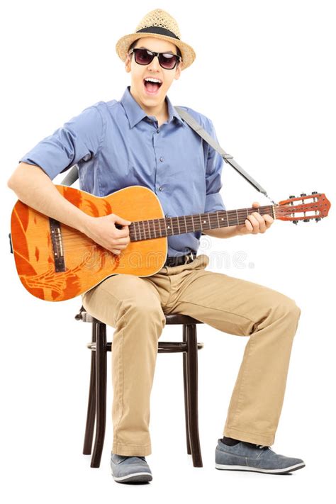 Young Man Sitting On A Chair And Playing Acoustic Guitar Stock Image
