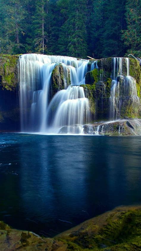 Stream Waterfall On Algae Covered Rocks Pouring On River Surrounded By