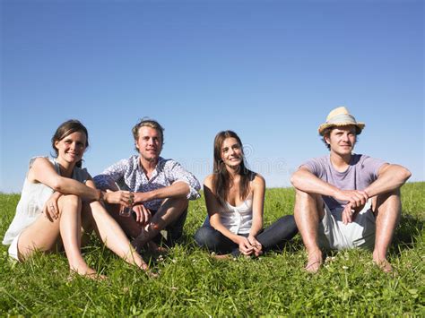 Four People Sitting On The Grass Stock Photo Image Of Friends Blue