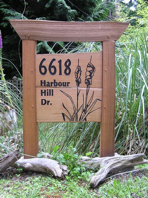 A Wooden Sign Sitting On The Side Of A Lush Green Field