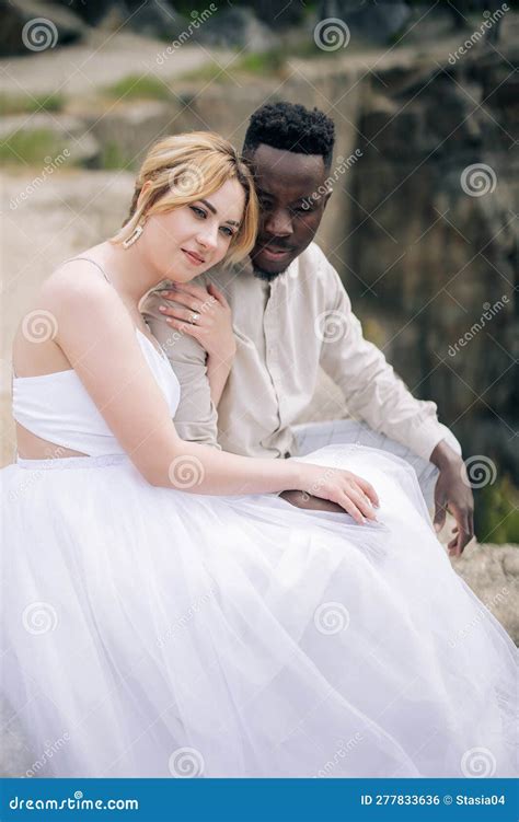 Dreaming Interracial Couple Newlyweds Sits On Rock Against Background