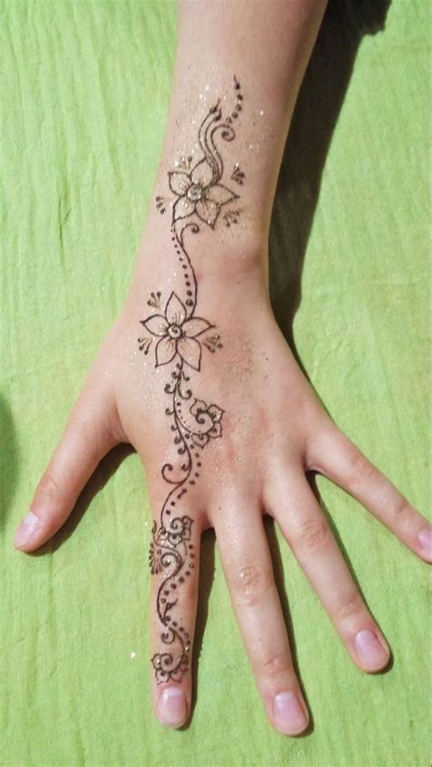 A Persons Hand With A Henna Tattoo On It Sitting On A Green Blanket