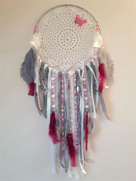 A Dream Catcher With Feathers And Beads Hanging On The Wall Next To A