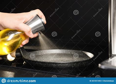 Woman Spraying Cooking Oil Onto Frying Pan On Stove Closeup Stock