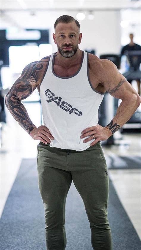 A Man With His Hands On His Hips Posing For The Camera In Front Of A Gym
