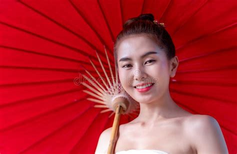 asian beautiful woman wear a luxury national costume and holding a red umbrella and a little