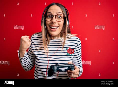 Young Blonde Gamer Woman Using Gamepad Playing Video Games Over Red