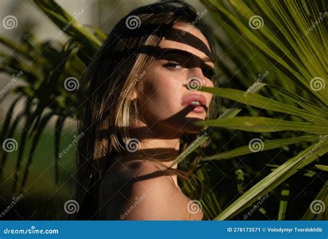 Closeup Portrait Of Young And Beautiful Woman With Perfect Smooth Tanned Skin In Tropical Leaves