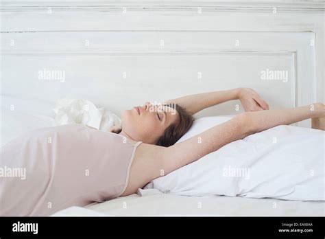 Woman Lying On Back In Bed Stretching Stock Photo Alamy