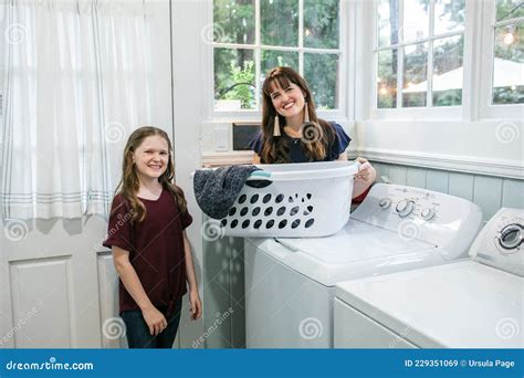 A Mother And Daughter Doing Laundry Chores Together In Their Natural Light Laundry Room Stock