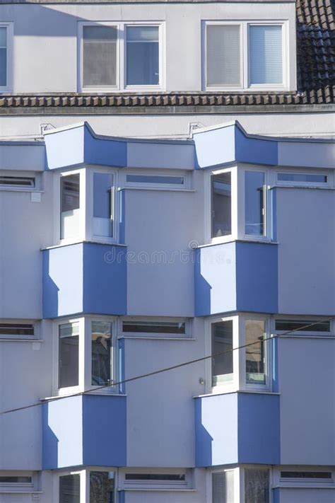 Light Blue Residential Building With Triangular Windows And Balconies