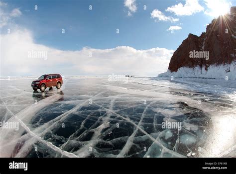 Red Off Roader Are Driving Along The Clear Ice Of A Frozen Lake Baikal