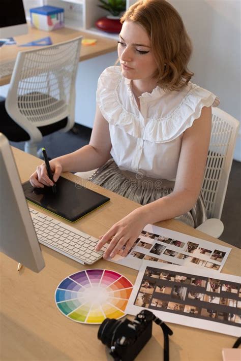 Female Graphic Designer Working On Graphics Tablet And Computer At Desk