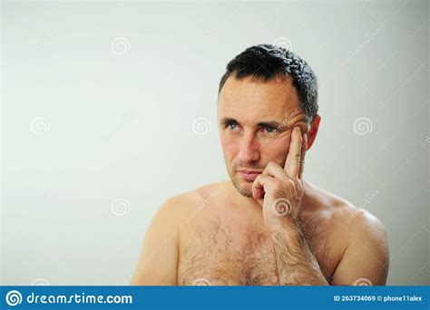 adult man with naked torso tired worries thinks about something he has sad tired eyes blue green