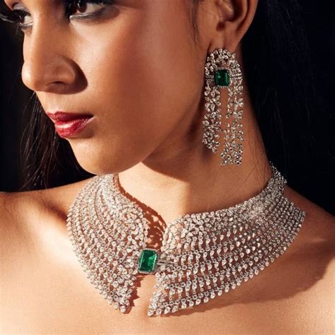 A Woman Wearing A Necklace And Earrings With Emeralds On The Neck In Front Of A Black Background