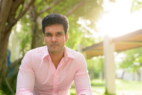 Young Handsome Indian Businessman Sitting At The Park Outdoors Stock