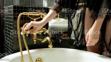 Close Up Of Womens Hands Turning On The Bath Tap To Fill The Bath With