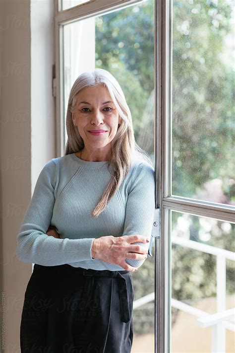 Confident Senior Lady Leaning On Office Window By Stocksy Contributor