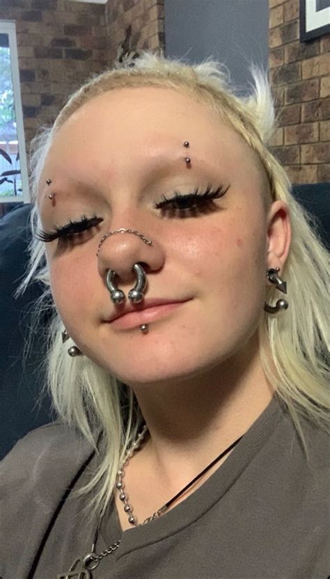 A Woman With Piercings On Her Nose And Nose Ring In Front Of Her Face