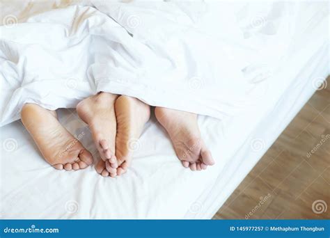 Close Up Legs Feet Of Two Lovers Couple Sleeping Side By Side Embracing Under Blanket White