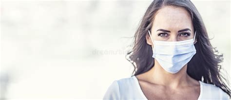 Serious Looking Young Woman Wearing A Disposable Face Mask On An