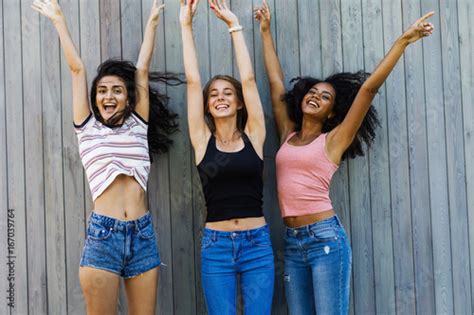 Multiracial Group Of Female Friends Having Fun Jumping With Raising