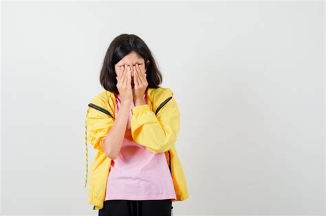 노란색 운동복을 입은 10대 소녀 얼굴에 손을 대고 화난 표정을 짓고 있는 티셔츠 전면 전망 무료 사진
