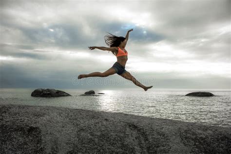 Woman Jumping On A Rock At Sunset On Bakovern Beach Cape Town Stock Image Image Of Overcast