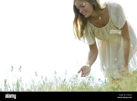 Young Woman Bending Over To Touch Tall Grass Stock Photo Alamy